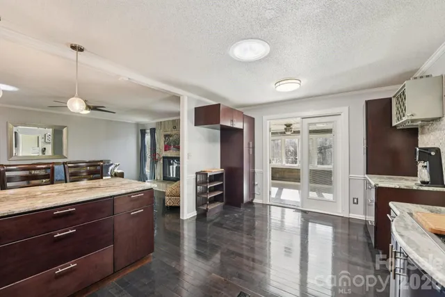 a view of living room kitchen with stainless steel appliances granite countertop cabinets and wooden floor