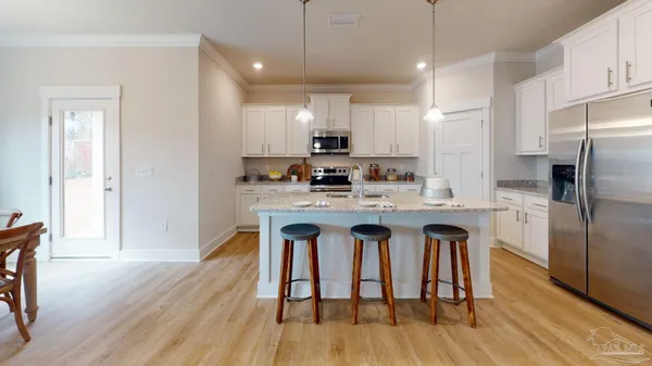 a kitchen with stainless steel appliances a dining table chairs stove refrigerator and cabinets