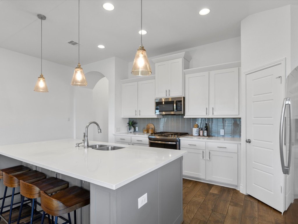 1009 Deer Rim Road Leander, TX 78641 - Photo 9 of 40 The kitchen boasts a large center island lined with inviting bar seating that is illuminated by designer pendants above.