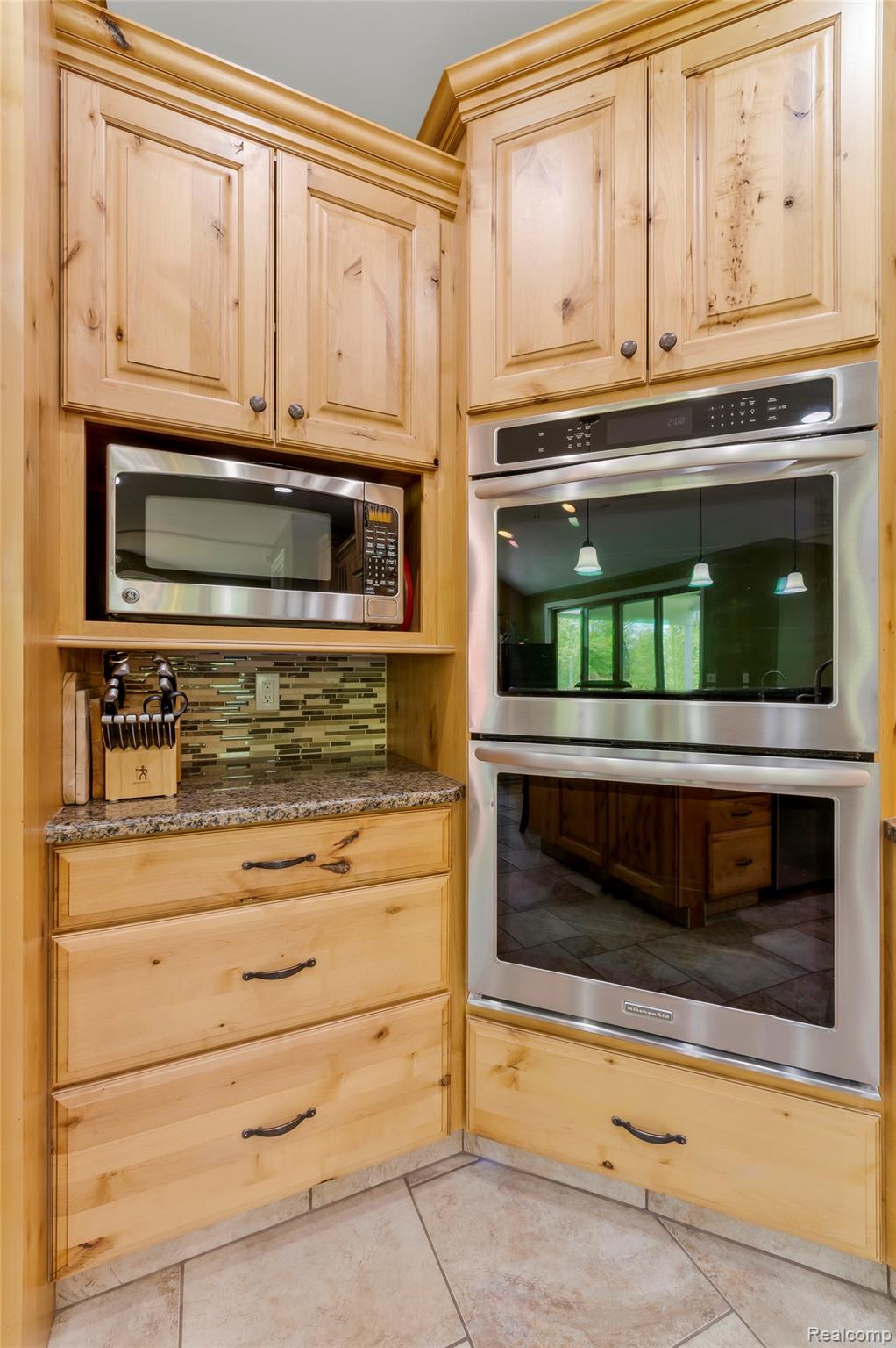 13085 Rohn Road Fenton, MI 48430 - Photo 8 of 52 Kitchen featuring stainless steel appliances, light wood finish cabinets, dark stone counters, backsplash, and light tile patterned flooring