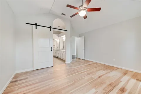 a view of empty room with wooden floor and fan