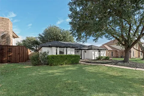 a front view of a house with a garden and trees