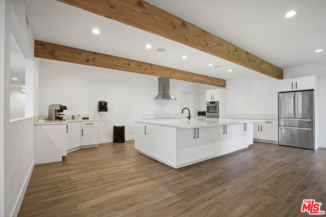 29500 Heathercliff Road, Unit A Malibu, CA 90265 - Photo 18 of 21 a large white kitchen with wooden floors and stainless steel appliances