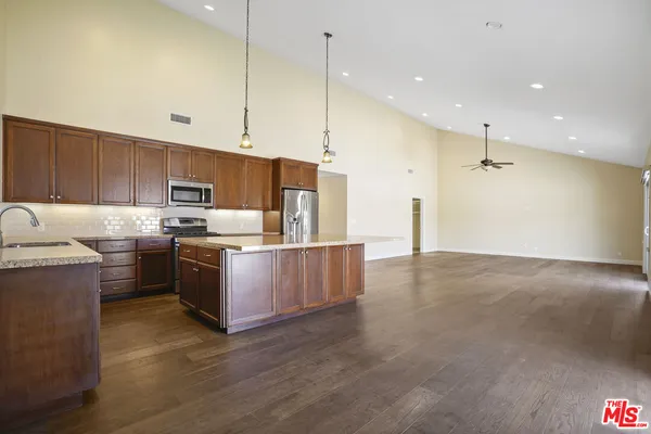 a kitchen with stainless steel appliances granite countertop a sink a stove and a refrigerator