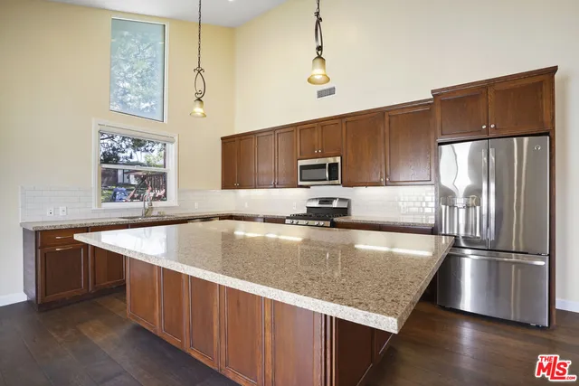a kitchen with stainless steel appliances granite countertop a sink a microwave a refrigerator and a stove