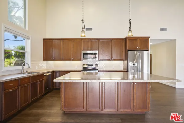 a kitchen with stainless steel appliances granite countertop a sink a stove and a refrigerator