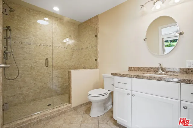 a bathroom with a granite countertop toilet a sink and a mirror