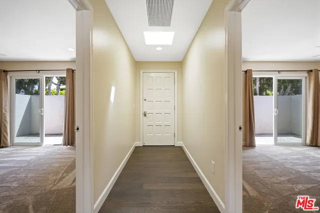 a view of a hallway with wooden floor and a bathroom