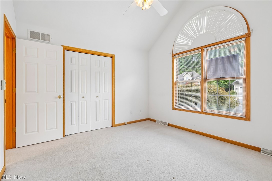 7007 Clingan Road, Unit 85 Youngstown, OH 44514 - Photo 27 of 46 Vaulted ceiling with ceiling fan, arched transom window, double-pane window, wood trim, and wall-to-wall carpeting