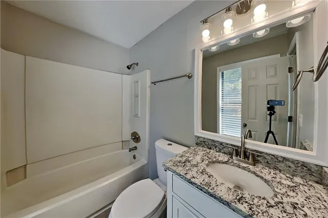 a bathroom with a granite countertop tub sink and mirror