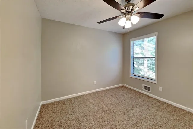 an empty room with windows and fan