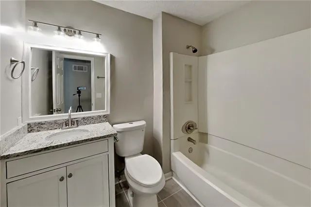 a bathroom with a granite countertop toilet a sink and a bathtub