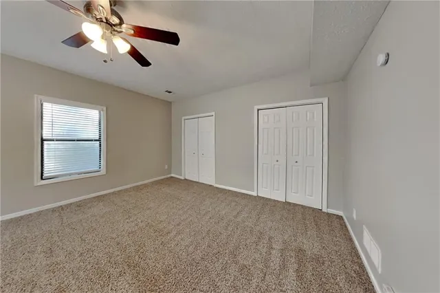 a view of an empty room with window and chandelier fan