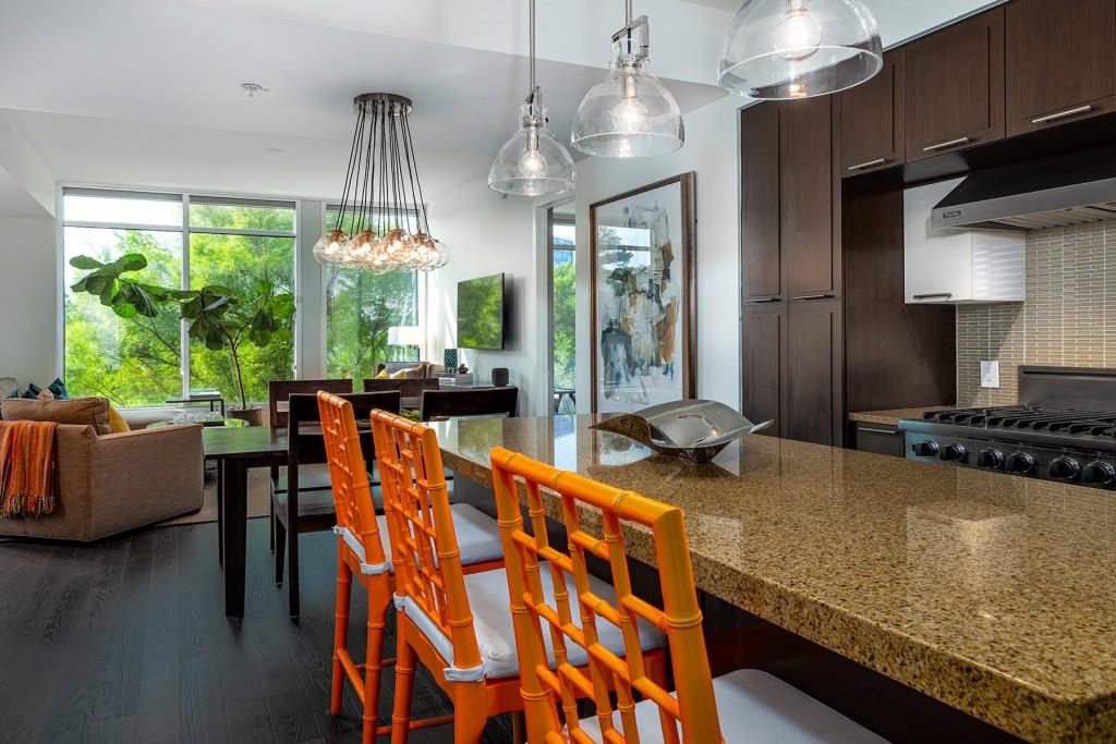 a kitchen with stainless steel appliances granite countertop a stove and a view of living room