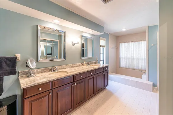 a spacious bathroom with a granite countertop double vanity sink a mirror and a bathtub