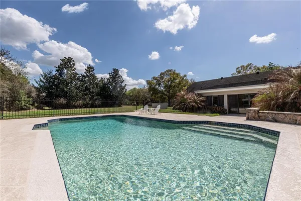 a view of house with swimming pool and yard