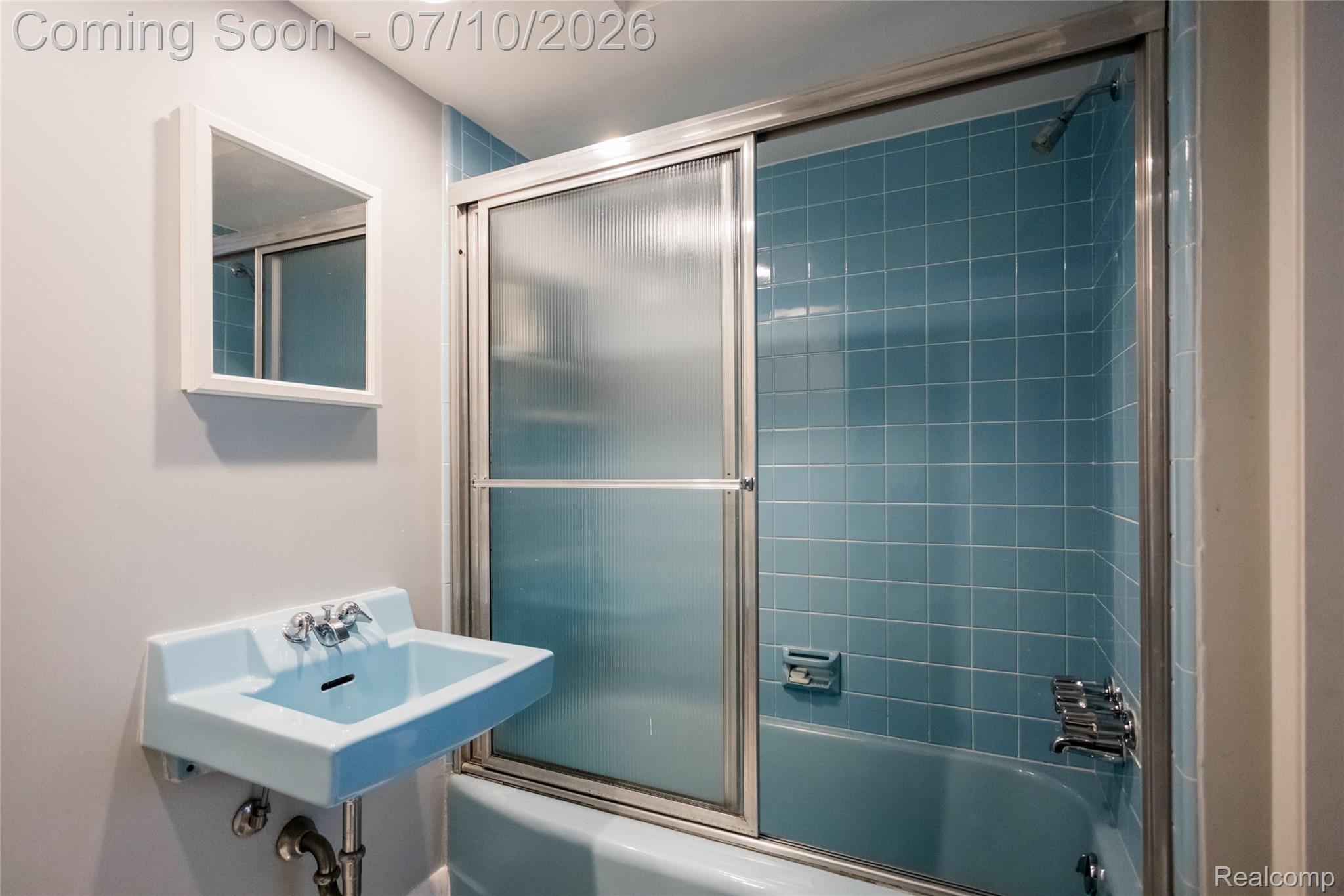 600 Middlesex Road Grosse Pointe, MI 48230 - Photo 26 of 43 Bathroom featuring a blue tiled shower surround with a sliding glass door, a matching blue wall-mounted sink with chrome fixtures, and a white framed medicine cabinet