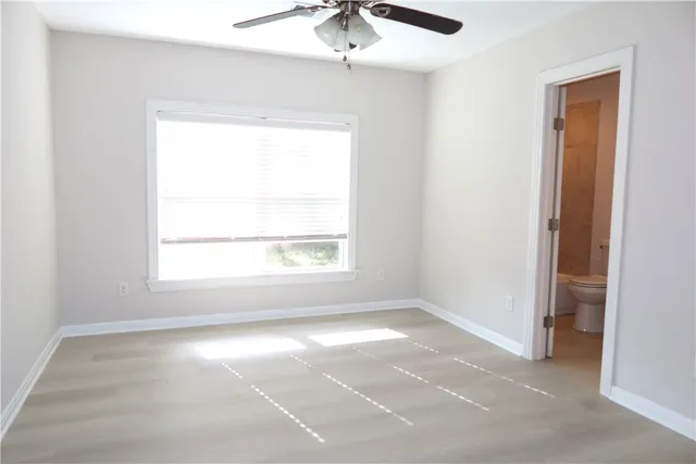an empty room with a window and a ceiling fan