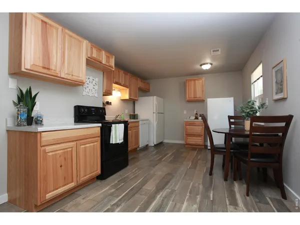 a kitchen with stainless steel appliances granite countertop wooden floors a stove and white cabinets