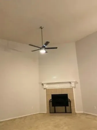 an empty room with a fireplace and a ceiling fan
