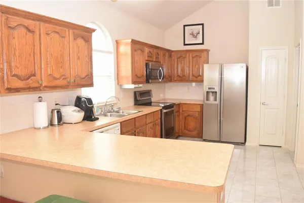 a kitchen with stainless steel appliances a sink a stove and a refrigerator with cabinets