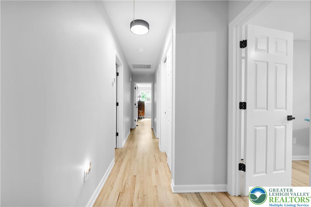 2011 Greenwood Road Allentown, PA 18103 - Photo 26 of 52 A well-lit corridor with blonde hardwood floors leads to various rooms, each promising unique spaces.