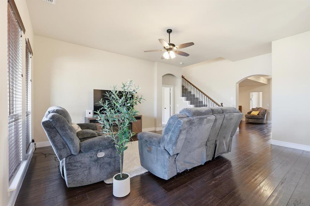 4609 Jasmine Trail Midlothian, TX 76065 - Photo 16 of 34 Living room with stairway, dark wood-style floors, a ceiling fan, and arched walkways