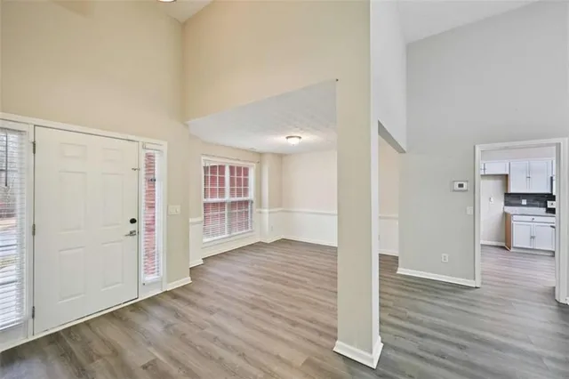 an empty room with wooden floor & windows and kitchen view