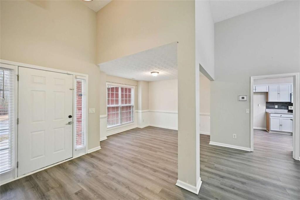 25 Castlehill Court Covington, GA 30016 - Photo 5 of 32 an empty room with wooden floor & windows and kitchen view