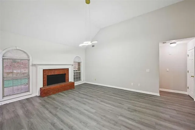 an empty room with wooden floor fireplace and windows