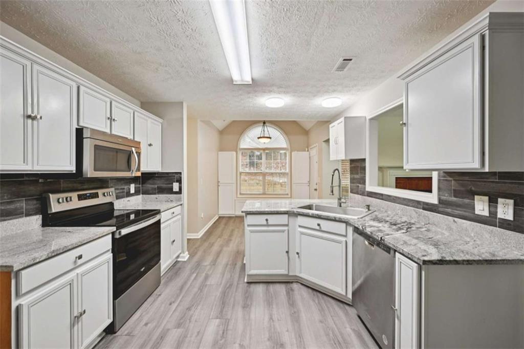 25 Castlehill Court Covington, GA 30016 - Photo 9 of 32 a kitchen with stainless steel appliances granite countertop refrigerator a stove top oven a sink dishwasher and white cabinets with wooden floor