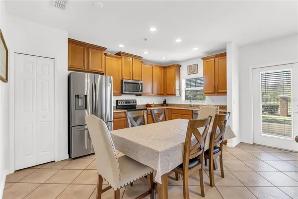 a kitchen with granite countertop a refrigerator a stove a sink a dining table and chairs