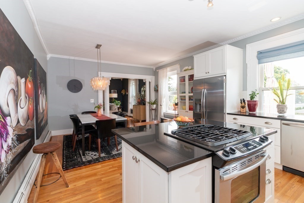 70 Cherry Street, Unit 1 Lynn, MA 01902 - Photo 19 of 40 a kitchen with a stove a refrigerator and a dining table with wooden floor