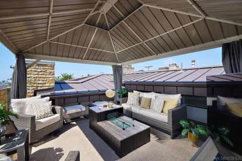 a view of a patio with couches and chairs under an umbrella