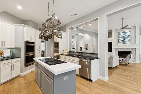 a kitchen with stainless steel appliances granite countertop a stove top oven a sink a counter space and living room view