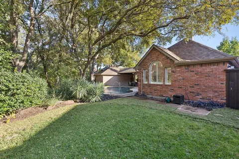 a view of a backyard with plants and large trees
