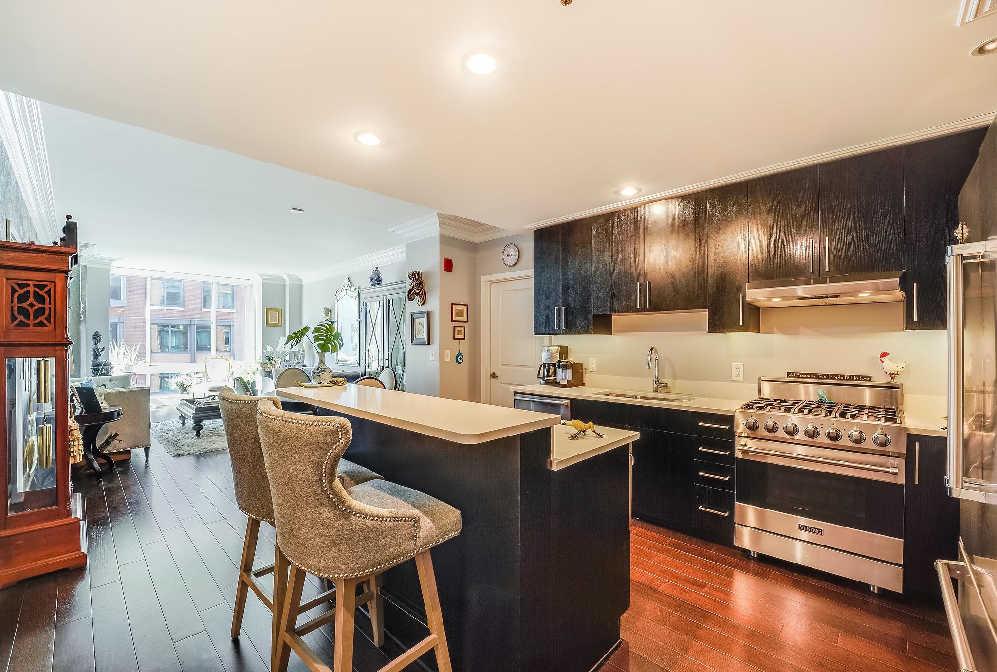 1100 Maxwell Lane, Unit 903 Hoboken, NJ 07030 - Photo 3 of 14 a kitchen with stainless steel appliances kitchen island granite countertop a stove a sink a refrigerator and chairs