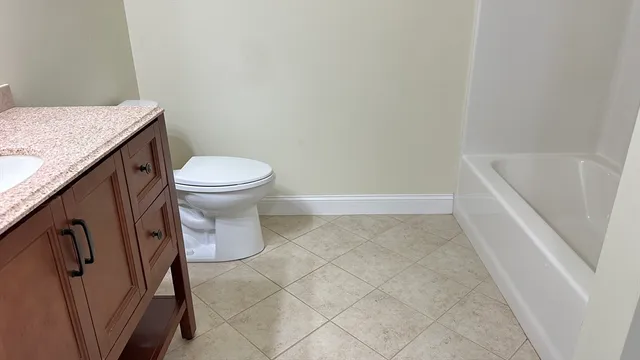 a bathroom with a granite countertop toilet and a sink