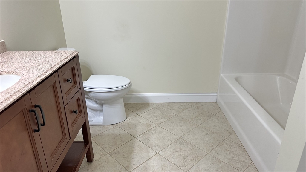 39 Fayette Street, Unit 102 Quincy, MA 02171 - Photo 11 of 24 a bathroom with a granite countertop toilet and a sink