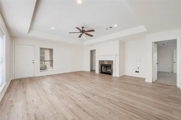 an empty room with wooden floor fireplace and windows