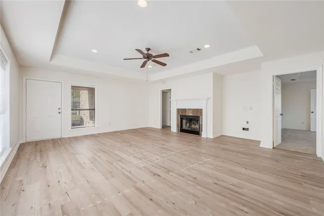 an empty room with wooden floor fireplace and windows