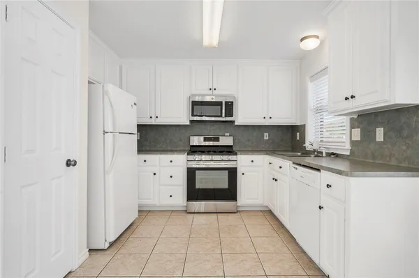 a kitchen with granite countertop white cabinets and stainless steel appliances