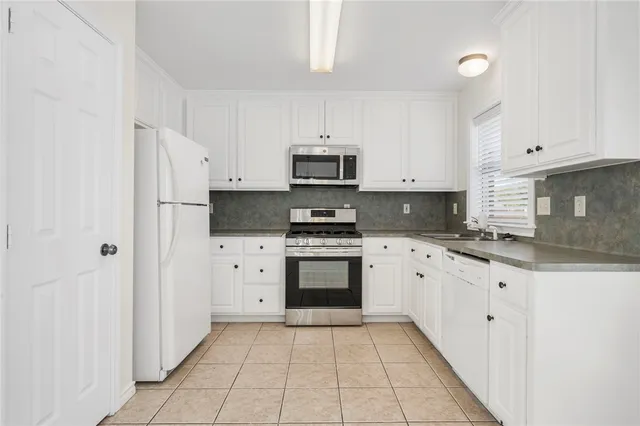a kitchen with granite countertop white cabinets and stainless steel appliances