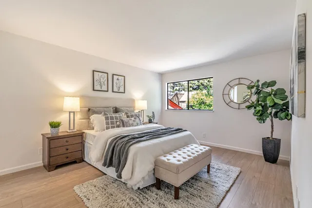 a bedroom with a bed a table and a potted plant