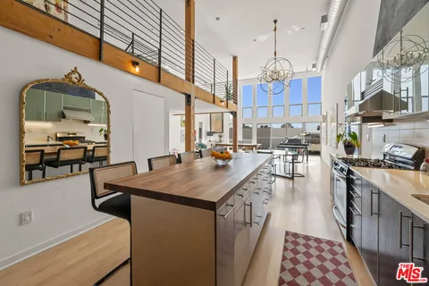 a kitchen with stainless steel appliances a dining table chairs and a refrigerator