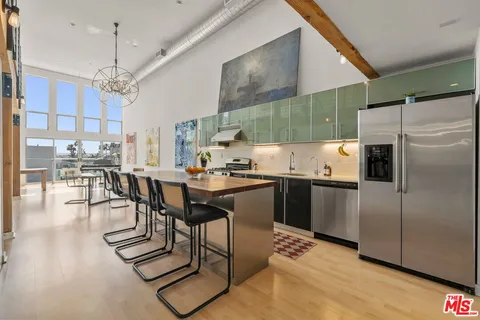 a kitchen with stainless steel appliances wooden floor and a refrigerator