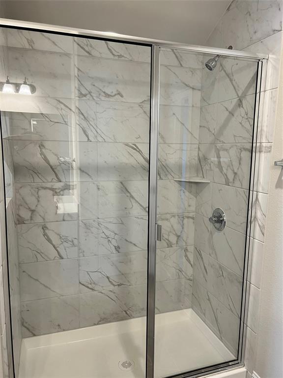 128 Free Stone Drive Georgetown, TX 78628 - Photo 13 of 29 Shower enclosure featuring a sliding glass door, white rectangular shower pan, white marble-patterned tile, chrome fixtures, and an integrated shower shelf