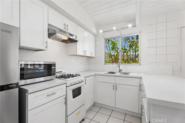 a kitchen with white cabinets appliances and a sink
