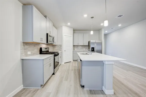 a kitchen with kitchen island a sink stainless steel appliances and cabinets