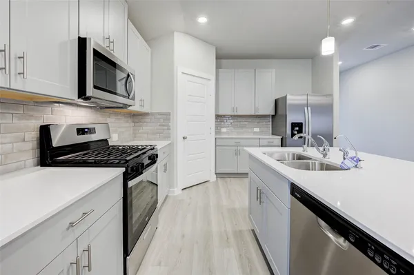 a kitchen with stainless steel appliances a sink dishwasher stove microwave and cabinets with wooden floor